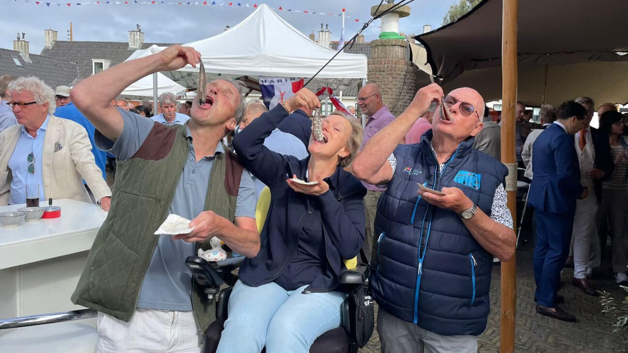 Wijkraadsleden happen een haring naar binnen