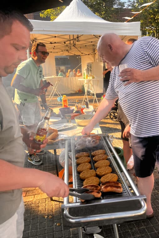 Mannen rond een BBQ met hamburgers