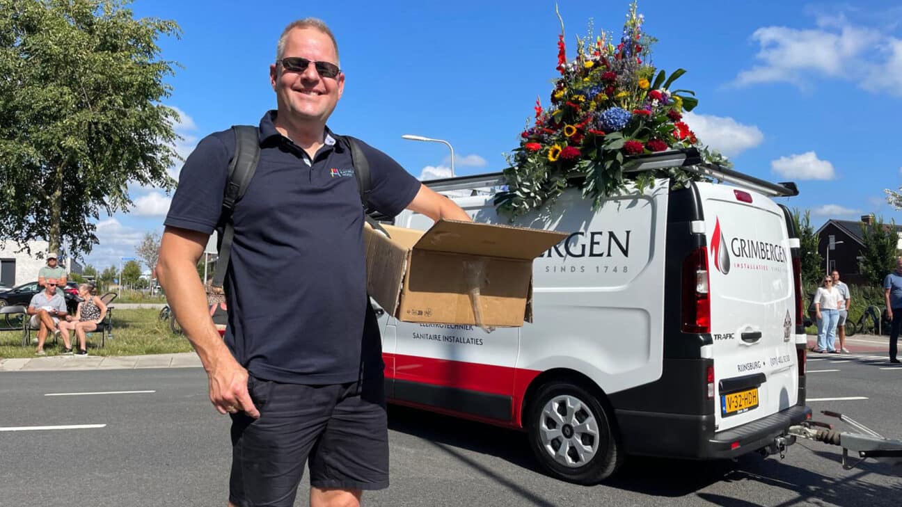 wijkraadsvoorzitter Jonathan Weegink deelt groeikaarten met QR-code van de community uit tijdens de Flower Parade Rijnsburg.
