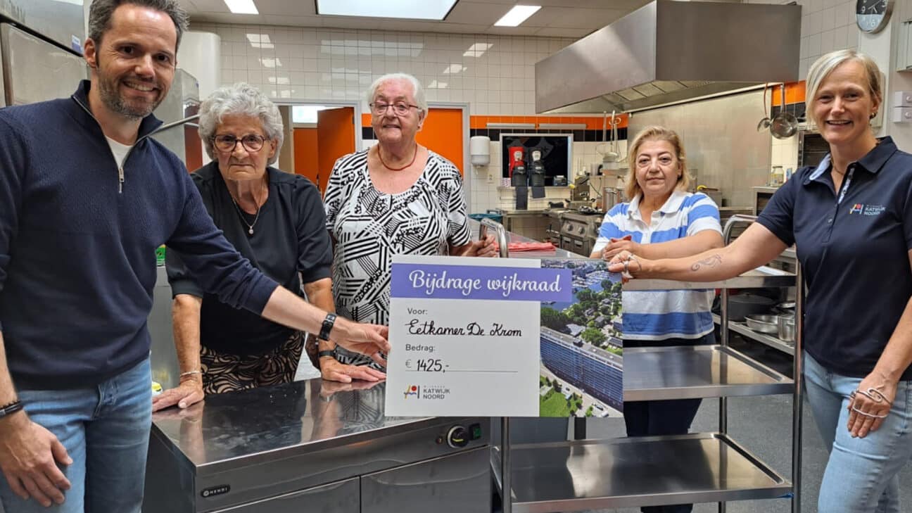 Wijkraadslid Jeanette overhandigt een cheque aan vrijwilligers van Eetkamer de Krom