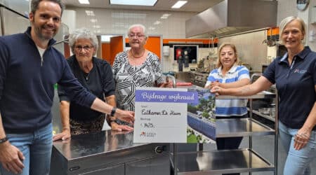 Wijkraadslid Jeanette overhandigt een cheque aan vrijwilligers van Eetkamer de Krom