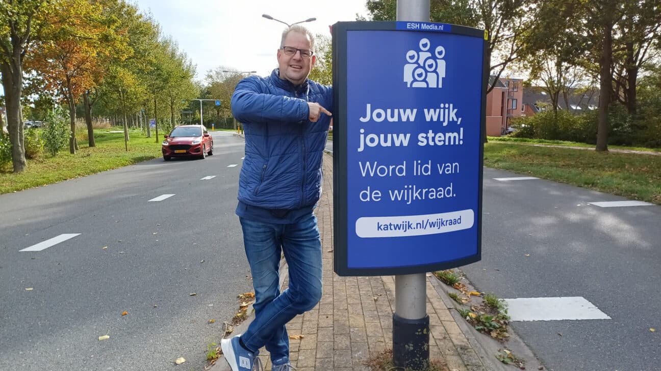 Voorzitter Jonathan Weegink bij een campagnebord langs de weg