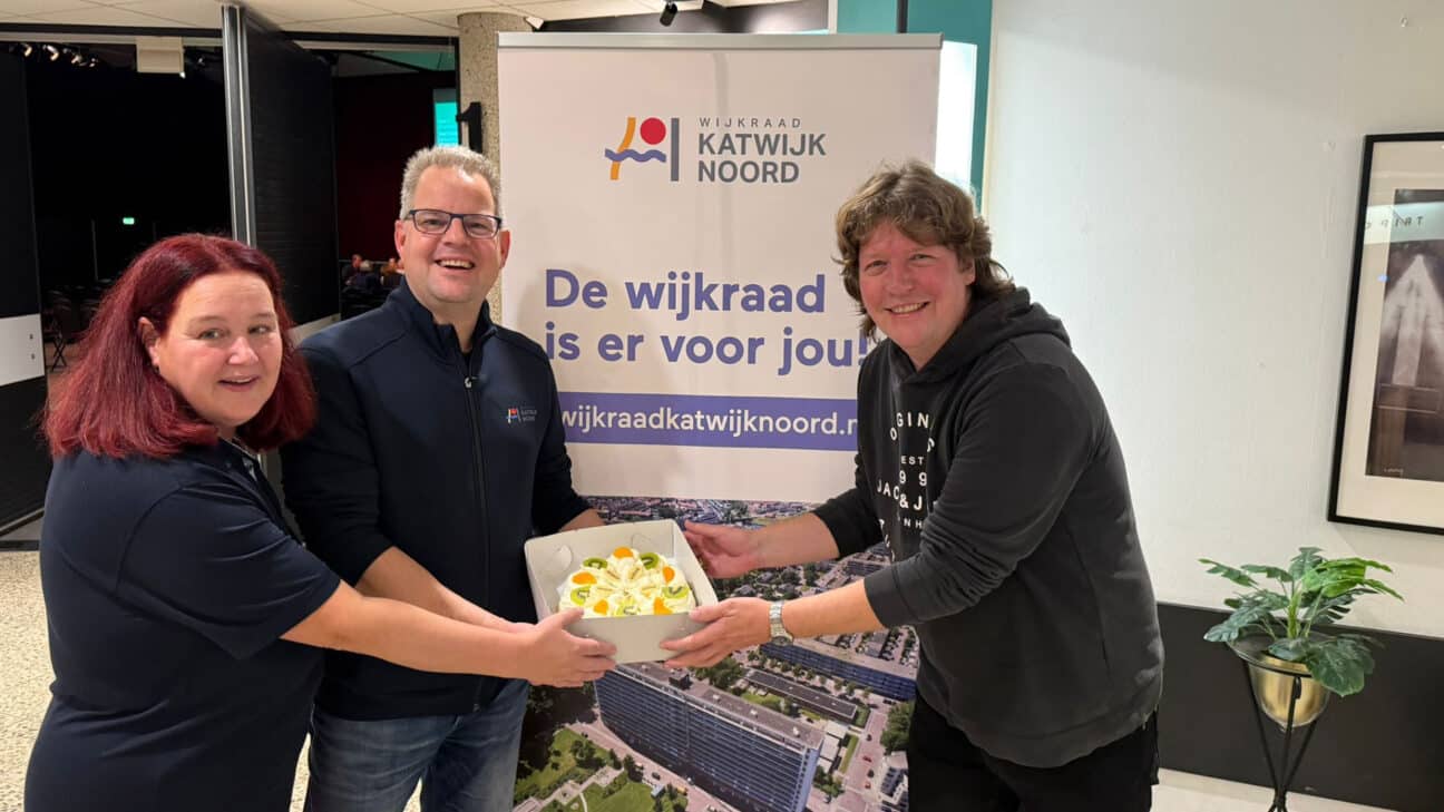 Een communitylid krijgt een taart overhandigd van wijkraad Katwijk Noord